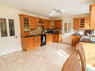 A kitchen with wooden cabinets black countertop and tiled floor at Seascape Lodge in Kenmare County Kerry
