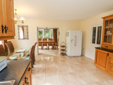 A kitchen with glass dining table chairs white refrigerator and wooden cabinets at Seascape Lodge Kenmare County Kerry