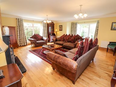 A living room with brown sofas and patterned cushions a wooden coffee table and large windows at Seascape Lodge in Kenmare County Kerry