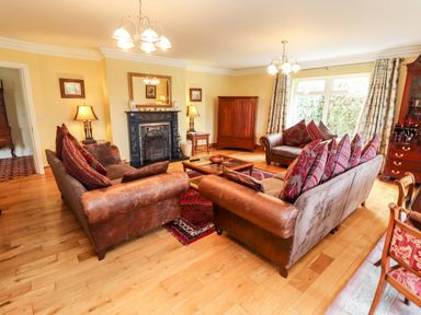 A living room with leather sofas and red cushions a fireplace and wooden furniture at Seascape Lodge in Kenmare County Kerry