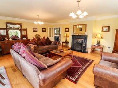 A living room with leather sofas a wooden coffee table a fireplace and a wooden cabinet at Seascape Lodge in Kenmare County Kerry