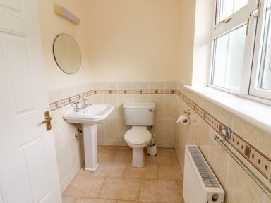 A bathroom with a sink toilet mirror window and radiator at Seascape Lodge in Kenmare County Kerry