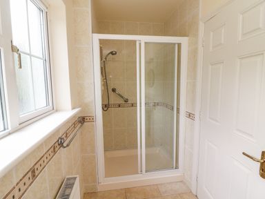 A bathroom with a glass shower enclosure a window a towel rail and a white door at Seascape Lodge in Kenmare County Kerry