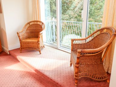 Two wicker chairs on carpeted floor near sliding glass door with balcony view at Seascape Lodge in Kenmare County Kerry