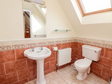 A bathroom with a pedestal sink a toilet and a mirror under a skylight window at Seascape Lodge in Kenmare County Kerry