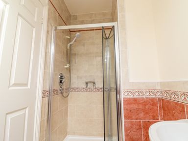 A shower with glass doors and tiled walls in a bathroom at Seascape Lodge in Kenmare County Kerry