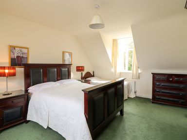 A bedroom with two beds wooden furniture and a window at Seascape Lodge Kenmare County Kerry