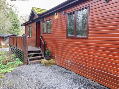 An exterior view of a wooden cabin with a small staircase and gravel pathway at Alfresco Lodge in Skiptory Howe 37B White Cross Bay near Windermere