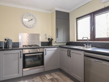 A kitchen with grey cabinets a built in oven a gas stove a sink and windows at Alfresco Lodge in Skiptory Howe 37B White Cross Bay near Windermere