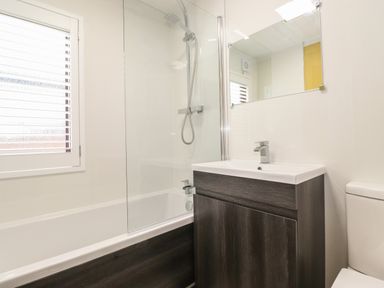 A bathroom with a bathtub shower combination a sink with cabinet and a toilet at Alfresco Lodge in Skiptory Howe 37B White Cross Bay near Windermere