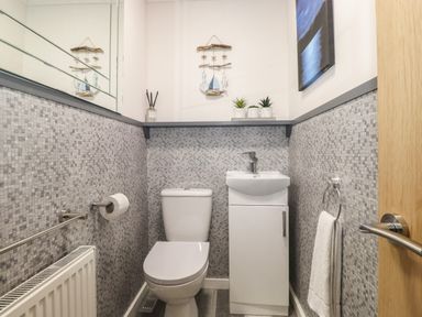 A bathroom with a toilet and a sink cabinet with towel and decorative items at Alfresco Lodge Skiptory Howe 37B White Cross Bay near Windermere