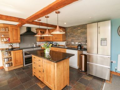 A kitchen with wooden cabinets a kitchen island stainless steel appliances and a flower vase at Apple Barn in South Molton