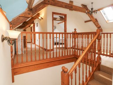 A staircase landing with wooden railing and exposed ceiling beams at Apple Barn in South Molton