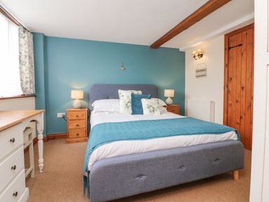 A bedroom with a grey upholstered bed and blue accent wall at Apple Barn in South Molton