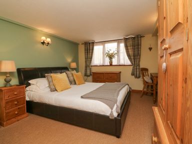 A bedroom with a bed bedside tables lamps a dresser and a desk at Apple Barn in South Molton