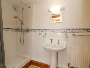 A bathroom with a shower area a sink mirror and radiator at Apple Barn in South Molton