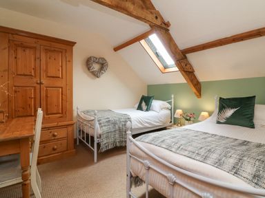 A bedroom with two single beds wooden wardrobe wooden desk and chair with skylight window at Apple Barn in South Molton
