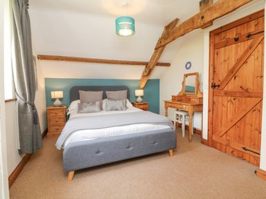 A bedroom with a bed lamps on bedside tables a wooden dressing table and a wooden door at Apple Barn in South Molton