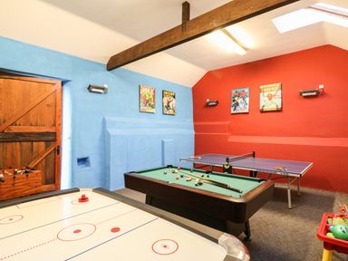 A games room with a pool table air hockey table ping pong table and foosball table with comic posters on walls at Apple Barn in South Molton