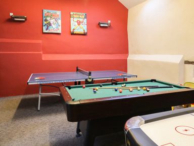 A game room with a pool table ping pong table and air hockey table with comic book posters on the wall at Apple Barn in South Molton