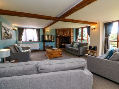 A living room with gray sofas a wooden coffee table a wall-mounted television and a brick fireplace at Apple Barn in South Molton