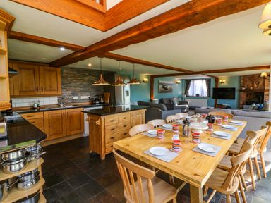 An open kitchen and dining area with wooden furniture and beams at Apple Barn in South Molton
