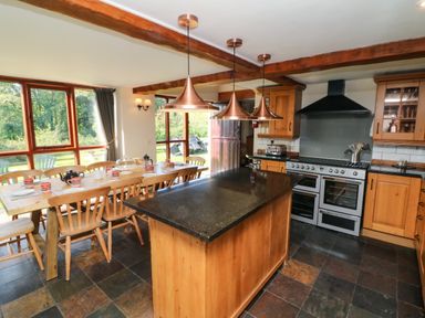 A kitchen with a wooden dining table set for tea and a central island at Apple Barn in South Molton