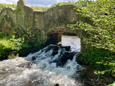 A stone bridge over a river with flowing water at Apple Barn in South Molton