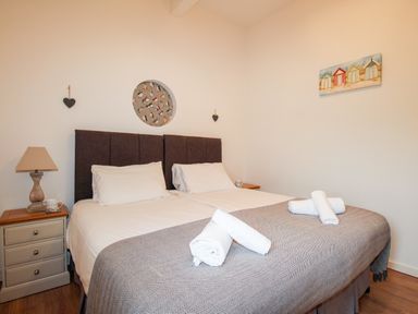 A bedroom with a double bed bedside tables lamps and wall decorations at Beside the Sea in Eype