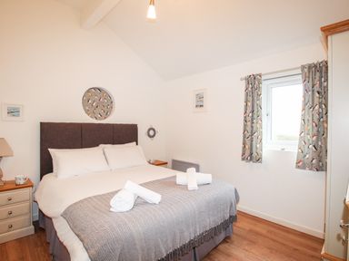 A bedroom with a double bed bedside tables and a window with curtains at Beside the Sea in Eype