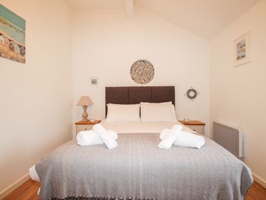 A bedroom with a bed with white towels and bedside tables with lamps at Beside the Sea in Eype