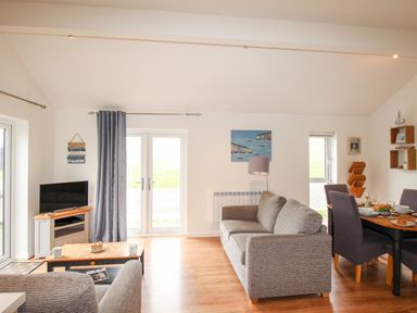A living room with sofas coffee table tv and dining table at Beside the Sea in Eype