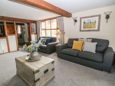 A living room with two gray sofas a wooden trunk coffee table with flowers and a framed picture on the wall at Hazel Barn in North Molton