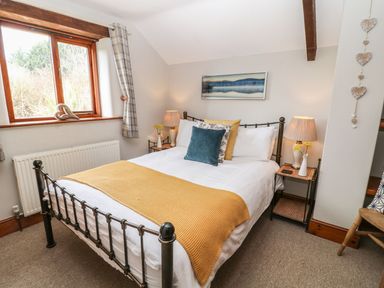 A bedroom with a metal bed frame and yellow bedspread at Hazel Barn in North Molton