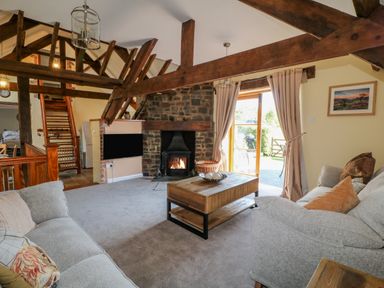 A living room with two sofas wooden beams stone fireplace and a coffee table at Oak Cottage in North Molton