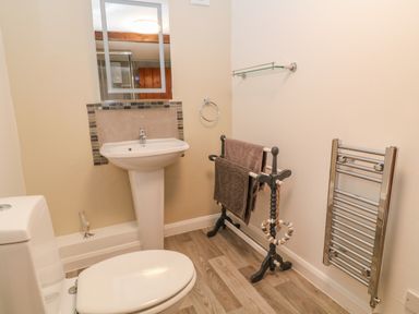 A bathroom with a toilet sink mirror towel rack and heated towel rail at Oak Cottage in North Molton