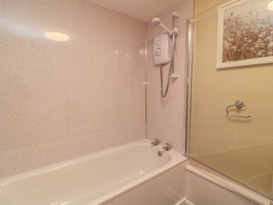 A bathroom with a bathtub shower unit and a glass shower screen at Oak Cottage in North Molton