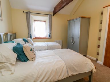 A bedroom with two single beds pillows and a wardrobe at Oak Cottage in North Molton