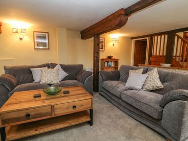 A living room with two gray sofas a wooden coffee table and wooden beams at The Hawthorns in North Molton