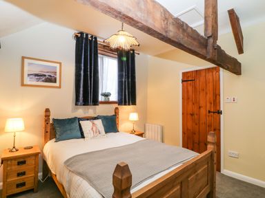 A bedroom with a wooden bed a gray blanket and two lamps on wooden bedside tables at The Hawthorns in North Molton