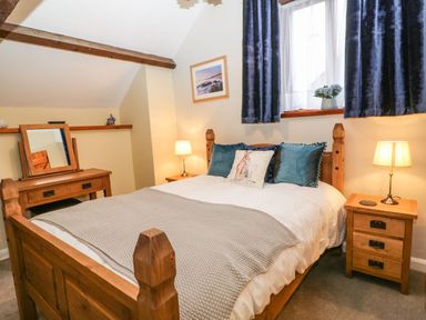 A bedroom with a wooden bed blue pillows bedside tables with lamps and a dressing table at The Hawthorns in North Molton