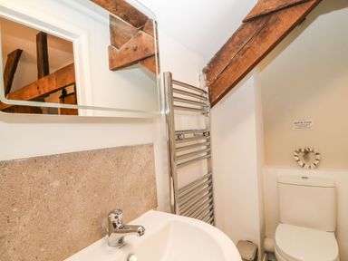 A bathroom with a sink faucet a heated towel rail a toilet and wooden ceiling beams at The Hawthorns in North Molton