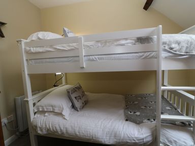 A bedroom with white bunk beds and sheep-themed pillows and blanket at The Hawthorns in North Molton