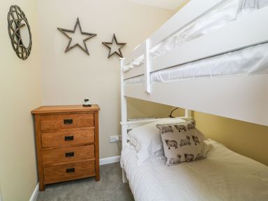A bedroom with a white bunk bed a wooden chest of drawers and star wall decorations at The Hawthorns in North Molton