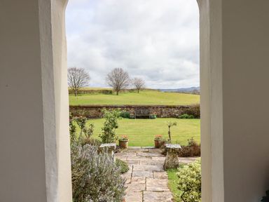 A stone pathway leading to a garden with a bench and green grass at Crablake Farmhouse in Exminster