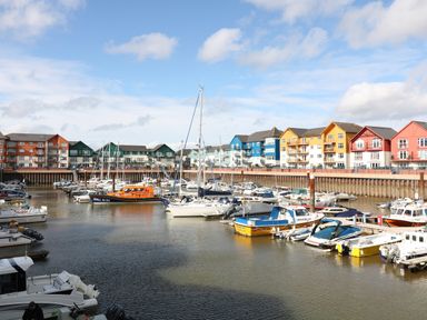 A marina with boats docked and colorful buildings along the water at Crablake Farmhouse in Exminster