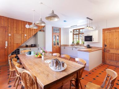 A kitchen with a wooden dining table and chairs and white cabinets at Crablake Farmhouse in Exminster