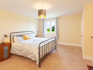 A bedroom with a metal bed frame side tables lamps window with curtains at Crablake Farmhouse in Exminster