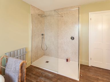 A bathroom with a walk in shower glass panel and towel rack at Crablake Farmhouse in Exminster