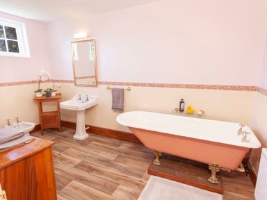 A bathroom with a clawfoot bathtub a pedestal sink and a bidet at Crablake Farmhouse in Exminster